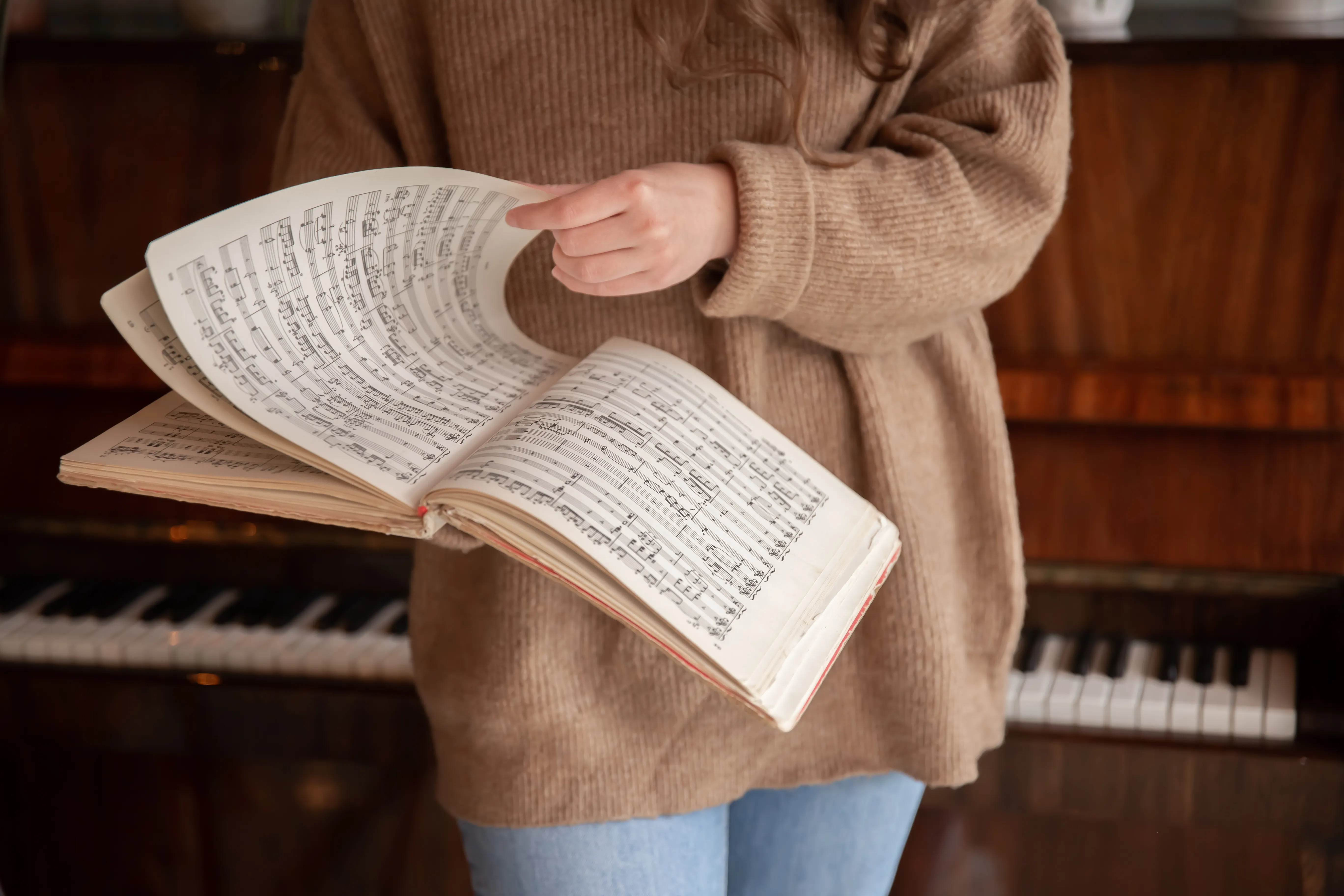 A person pointing to musical notation in an open score beside a piano