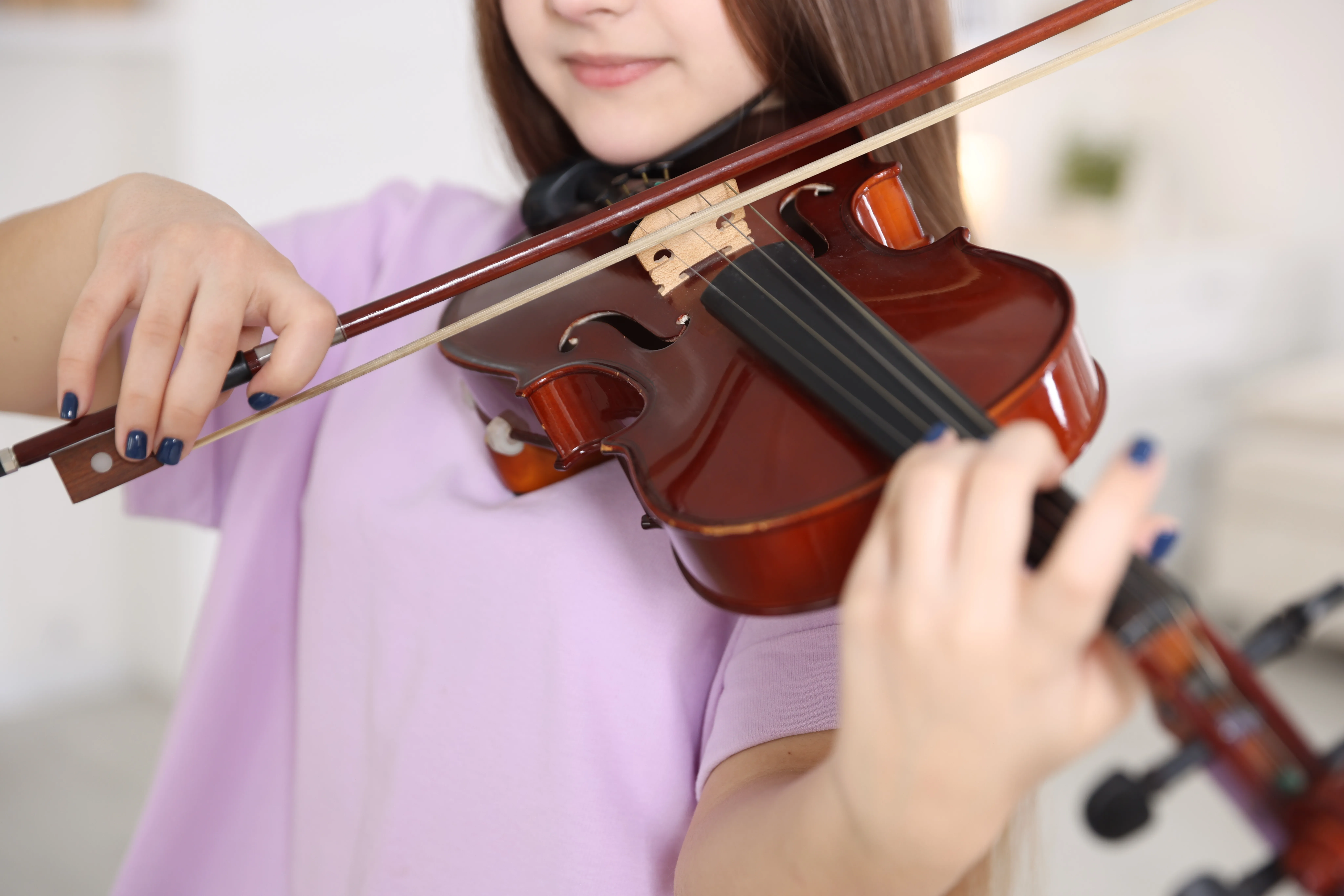 Close-up of a young student playing the violin, with the bow hand in focus.